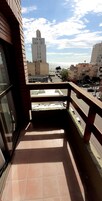 Un balcón con vista a un paisaje urbano, que incluye edificios y un cielo despejado.