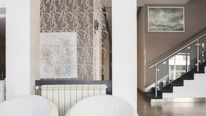 Un interior moderno con dos sillas blancas, un radiador y una escalera.