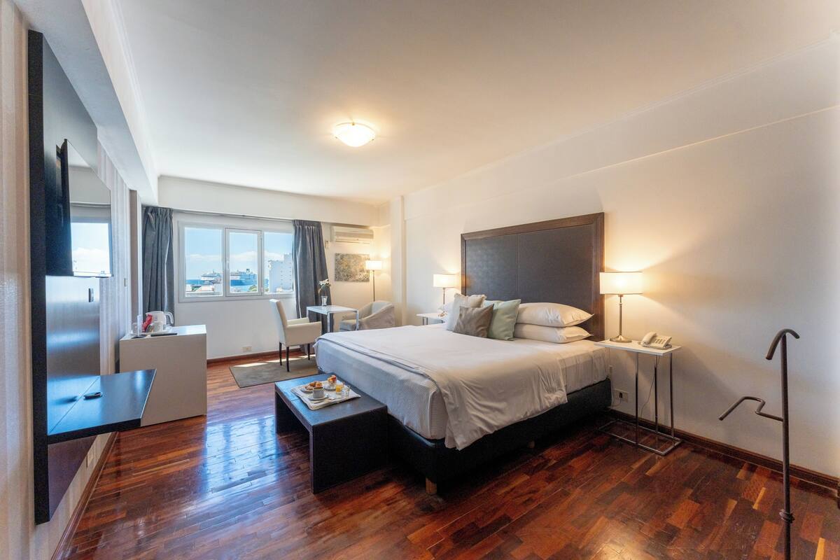 Une chambre d’hôtel avec un grand lit, des tables de chevet, un bureau, une chaise et une vue sur la ville.