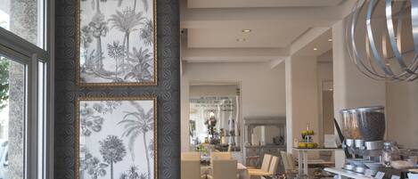A modern dining area with a long table, chairs, and a buffet with various food items and condiments.