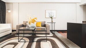 Una sala de estar moderna con un sofá, dos mesas auxiliares, una mesita lateral y un jarrón decorativo con flores.