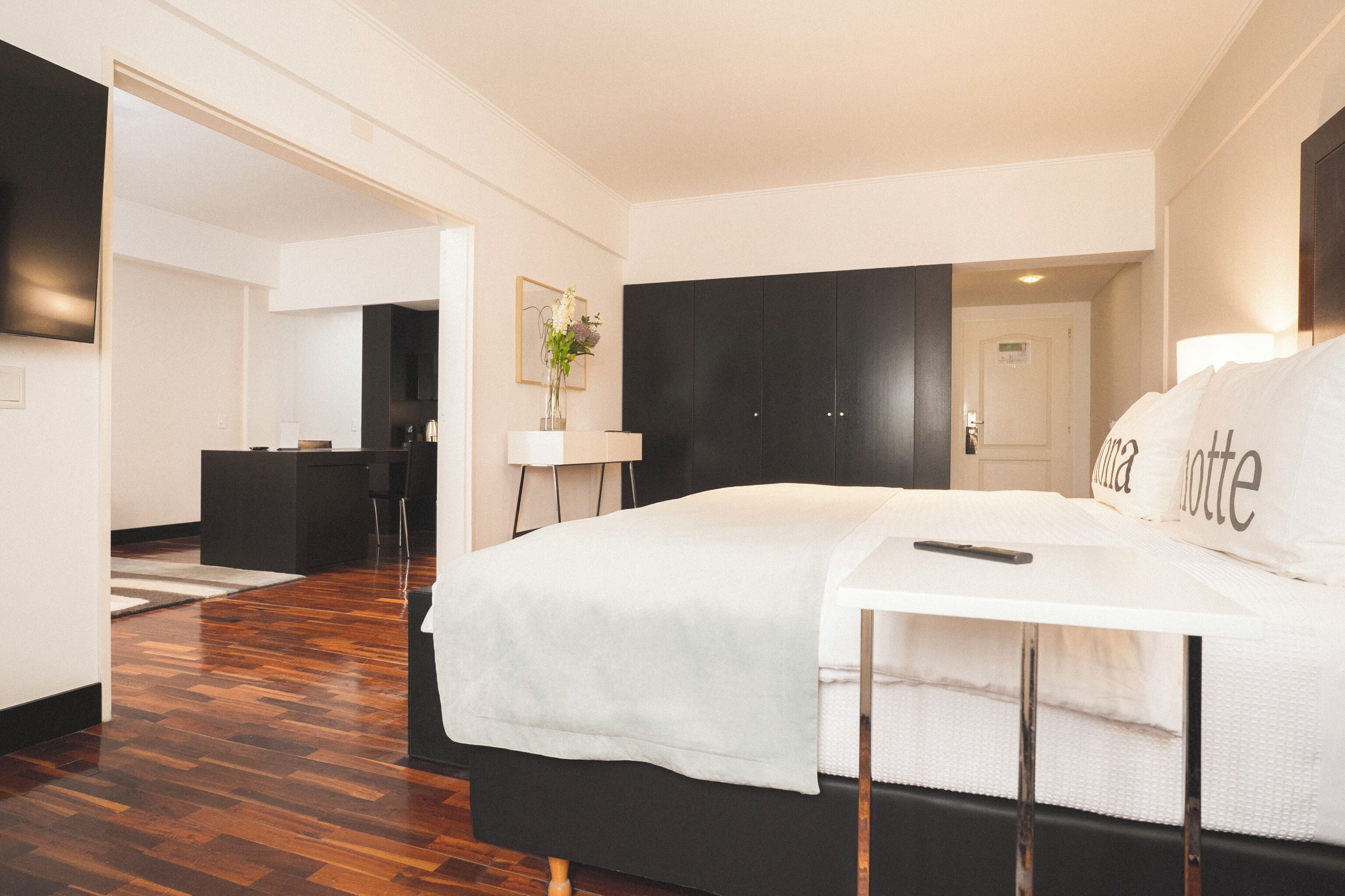 Una habitación de hotel moderna con una cama grande, un escritorio y un televisor de pantalla plana.