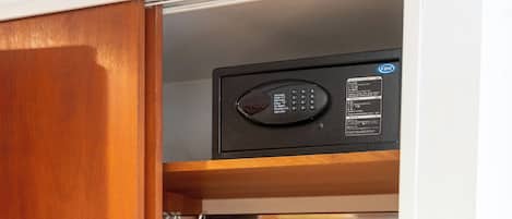 A wooden closet with a microwave on top, a hanging rack, and a vacuum cleaner.