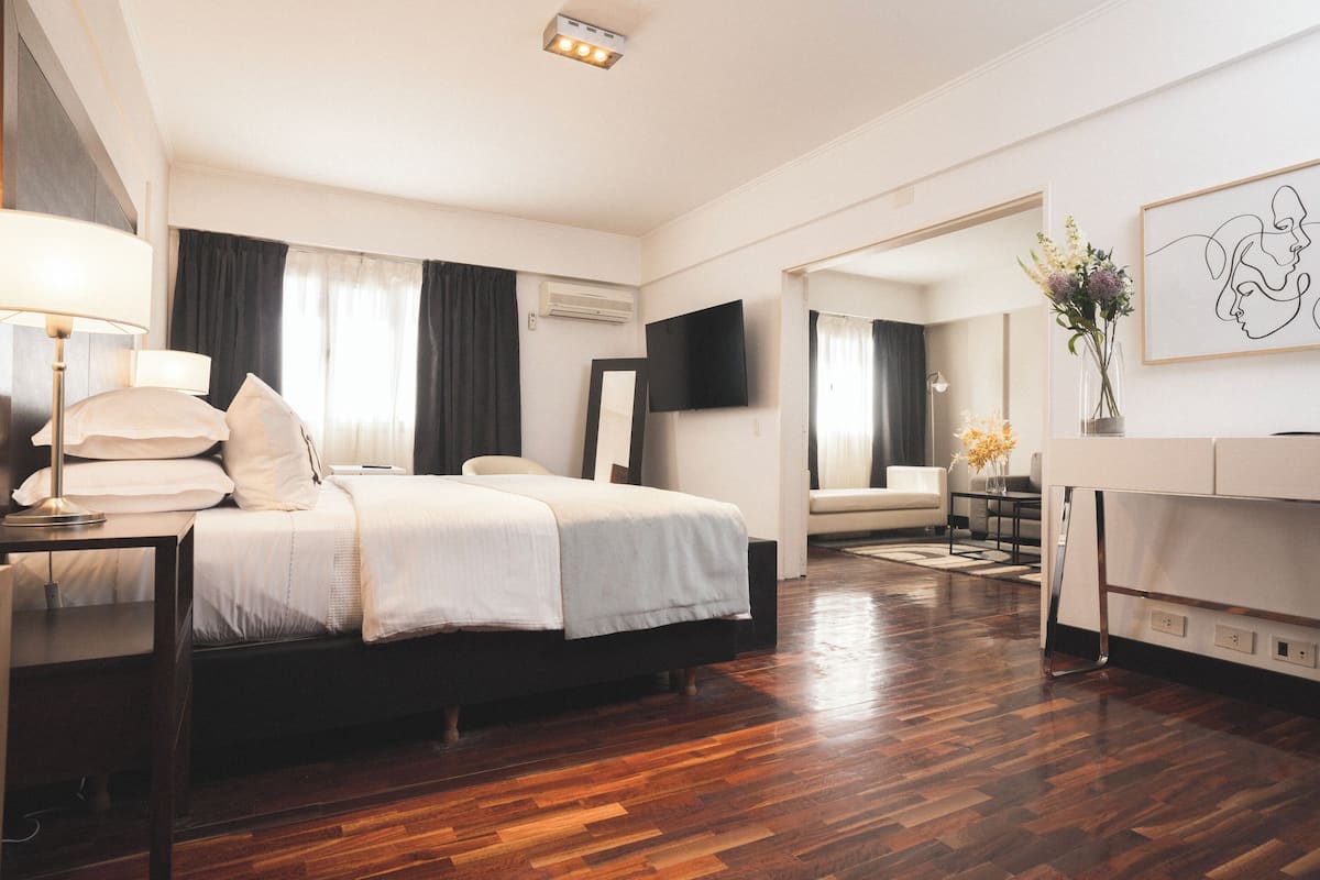 Une chambre moderne avec un grand lit, des tables de chevet, un téléviseur à écran plat et un miroir.