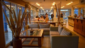 Un espacio interior amplio con asientos, una zona de bar y grandes ventanales que dejan entrar luz natural.