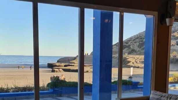 Una habitación con un ventanal grande con vistas a la playa, un sofá, una mesita de café y un pequeño adorno.