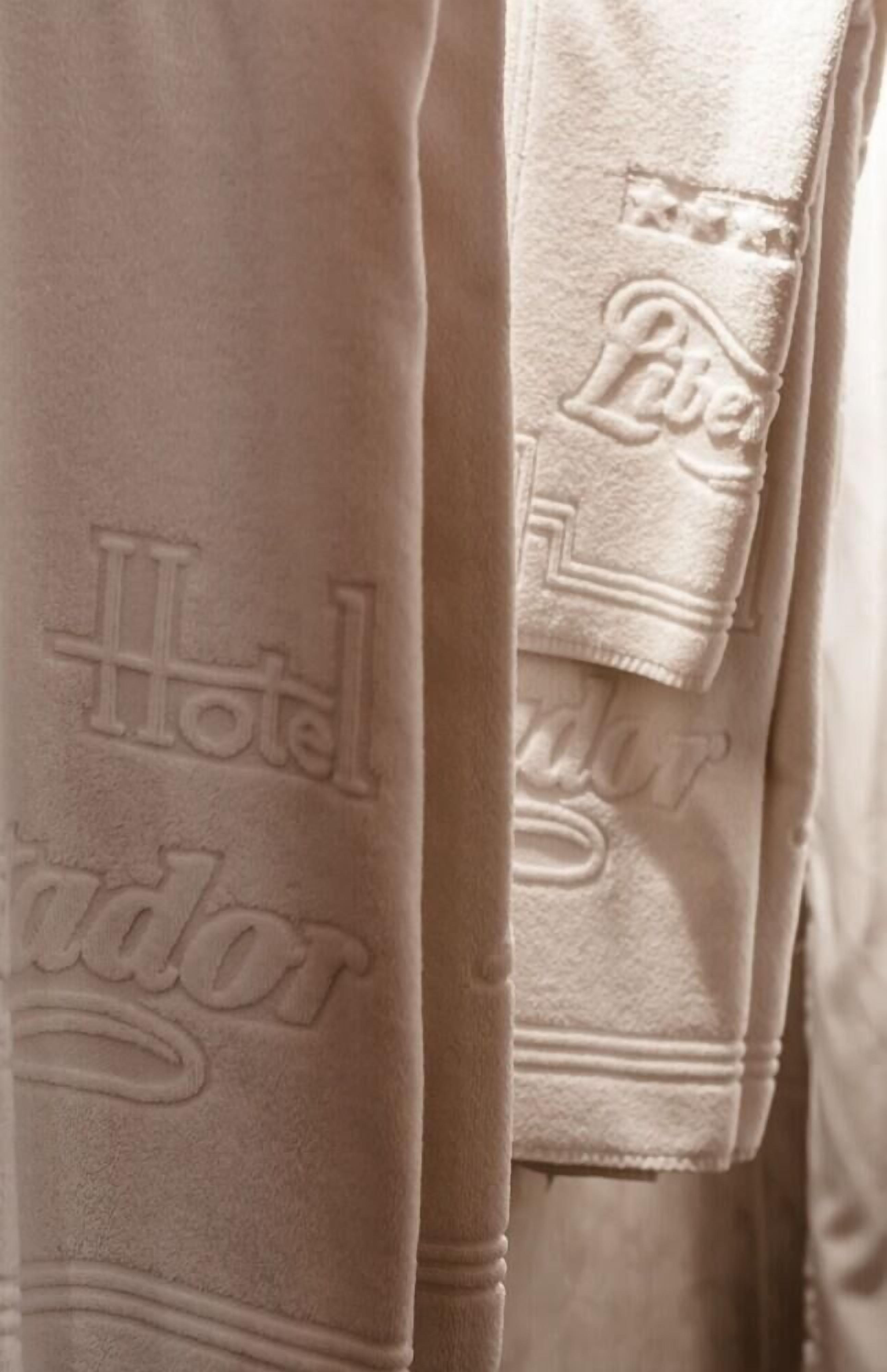 Toalla de hotel con texto en relieve que incluye 'Hotel' y 'Labe'.