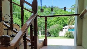 A wooden staircase with a glass balustrade leading to a patio area. - San Pedro Hotel (Rio Ceballos)