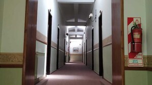 A long, narrow hallway with carpeted floors and wooden doors on both sides. - San Pedro Hotel (Rio Ceballos)