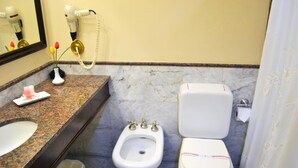 A bathroom with a marble sink, bidet, toilet, and a hairdryer on the wall. - Opera Hotel (Rio Cuarto)