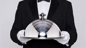 A person in a black tuxedo holding a silver cloche. - Opera Hotel (Rio Cuarto)