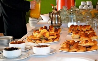 Un bufé de desayuno con diversos pasteles, mermeladas y una cafetera.