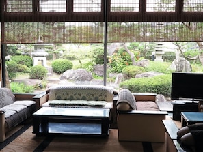 A traditional Japanese-style room with tatami flooring, a low table, and a sofa. - Yumeya Hanatsukushi (Awara)