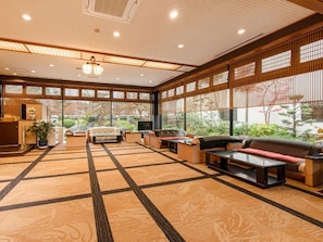 A spacious room with a traditional Japanese aesthetic, featuring tatami flooring, a low table, and a sofa. - Yumeya Hanatsukushi (Awara)