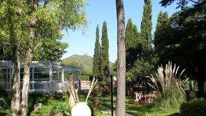Un jardín con un jarrón blanco grande, un banco de madera y un letrero que dice "Blumio".