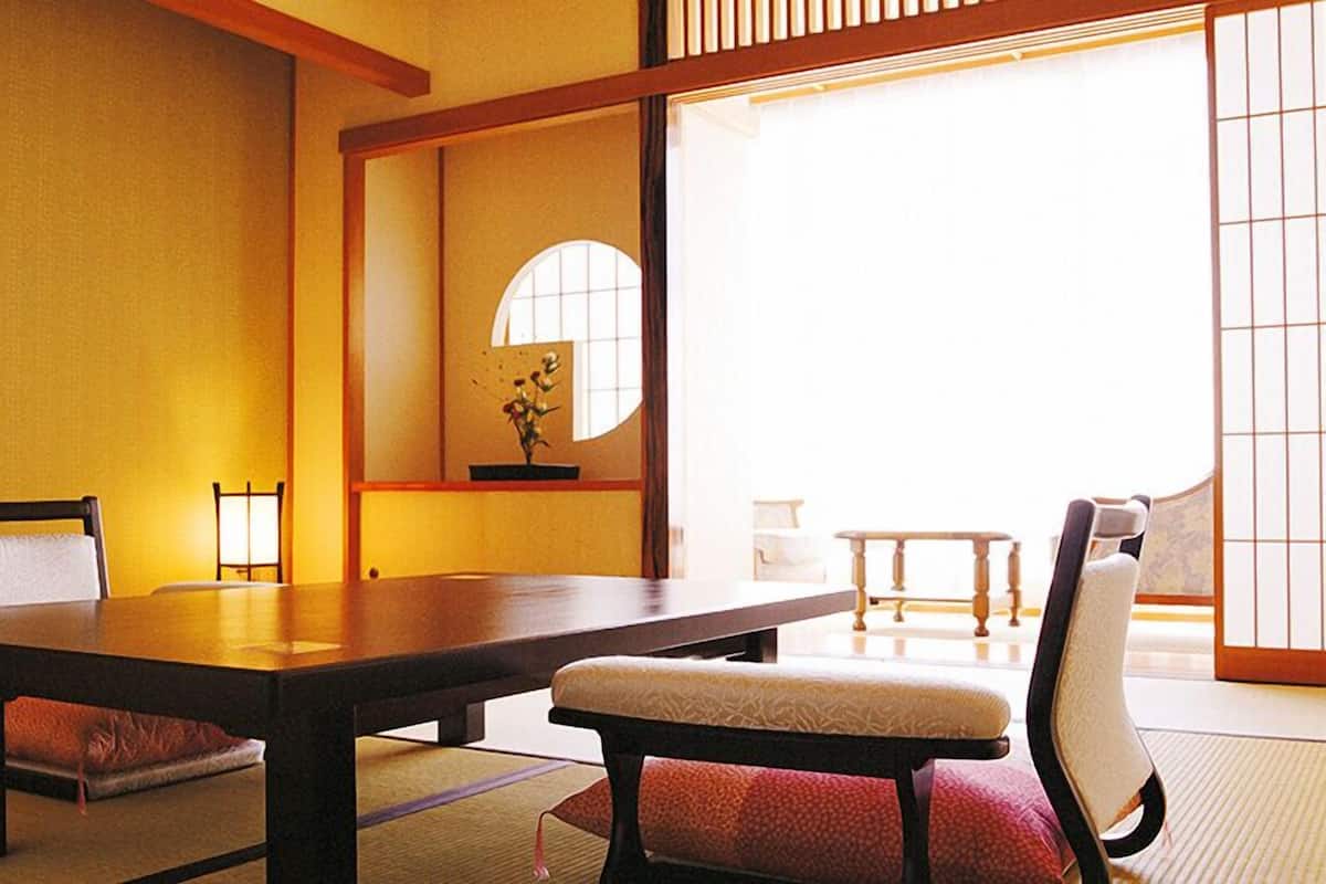 A traditional Japanese room with tatami flooring, a low table, and two chairs.