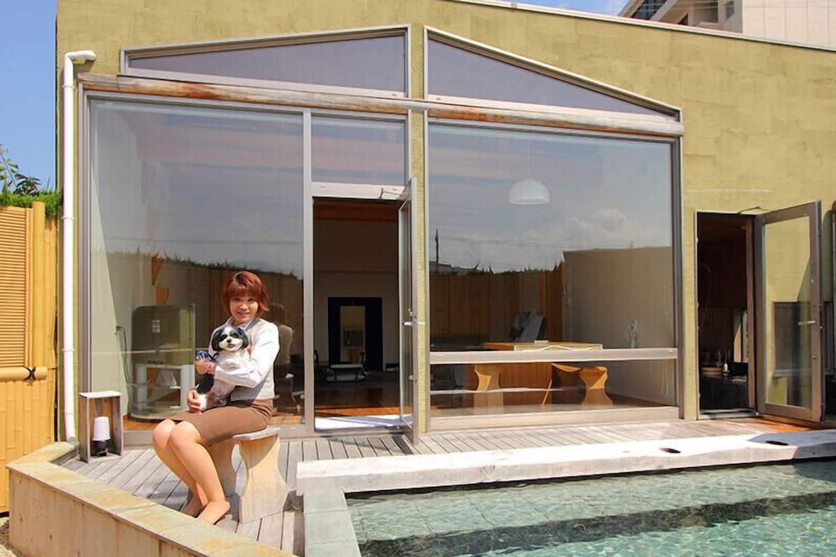 A modern house with a glass-enclosed patio, a pool, and a wooden deck.