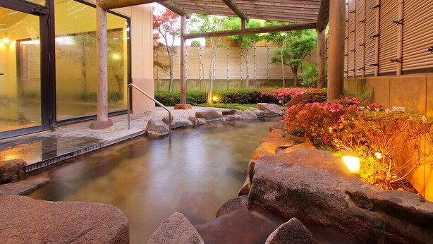 A tranquil indoor garden with a koi pond, stone pathways, and a wooden fence. - Hanaisawa (Ryokan) (Fuefuki)