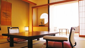 A traditional Japanese room with tatami flooring, a low table, and two chairs.