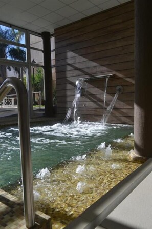 A hot tub with water jets, surrounded by wooden walls and a tiled floor. - Hotel Plaza (Colän)