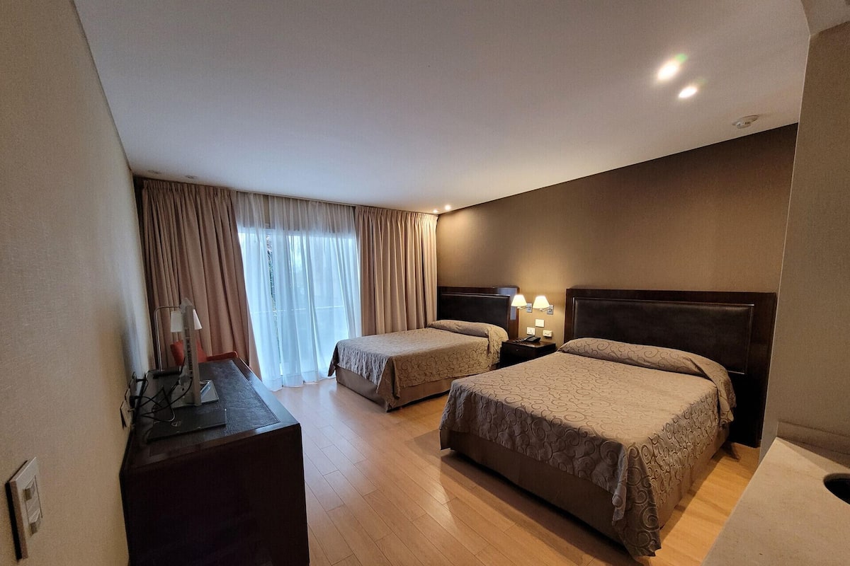Habitación de hotel con dos camas, un escritorio y una silla.