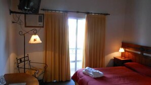 A hotel room with a bed, a chair, a table, a lamp, and a television. - Piedras del Lago Hotel (Federaciän)