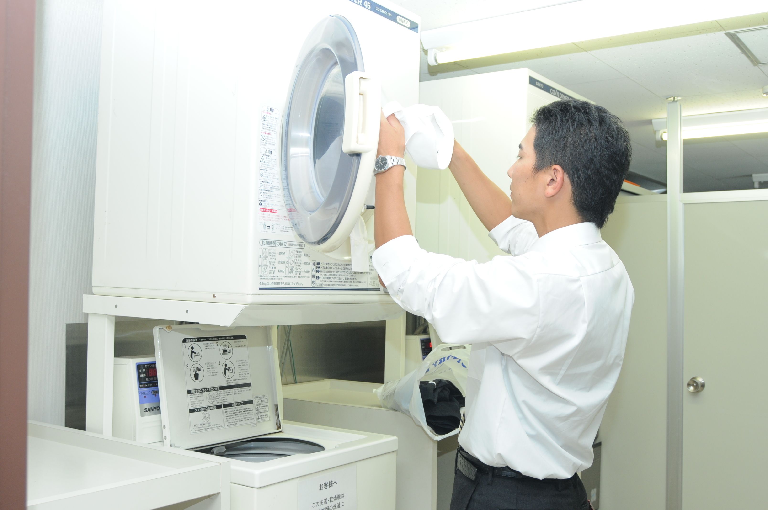 A person operating a large industrial washing machine in a commercial setting.