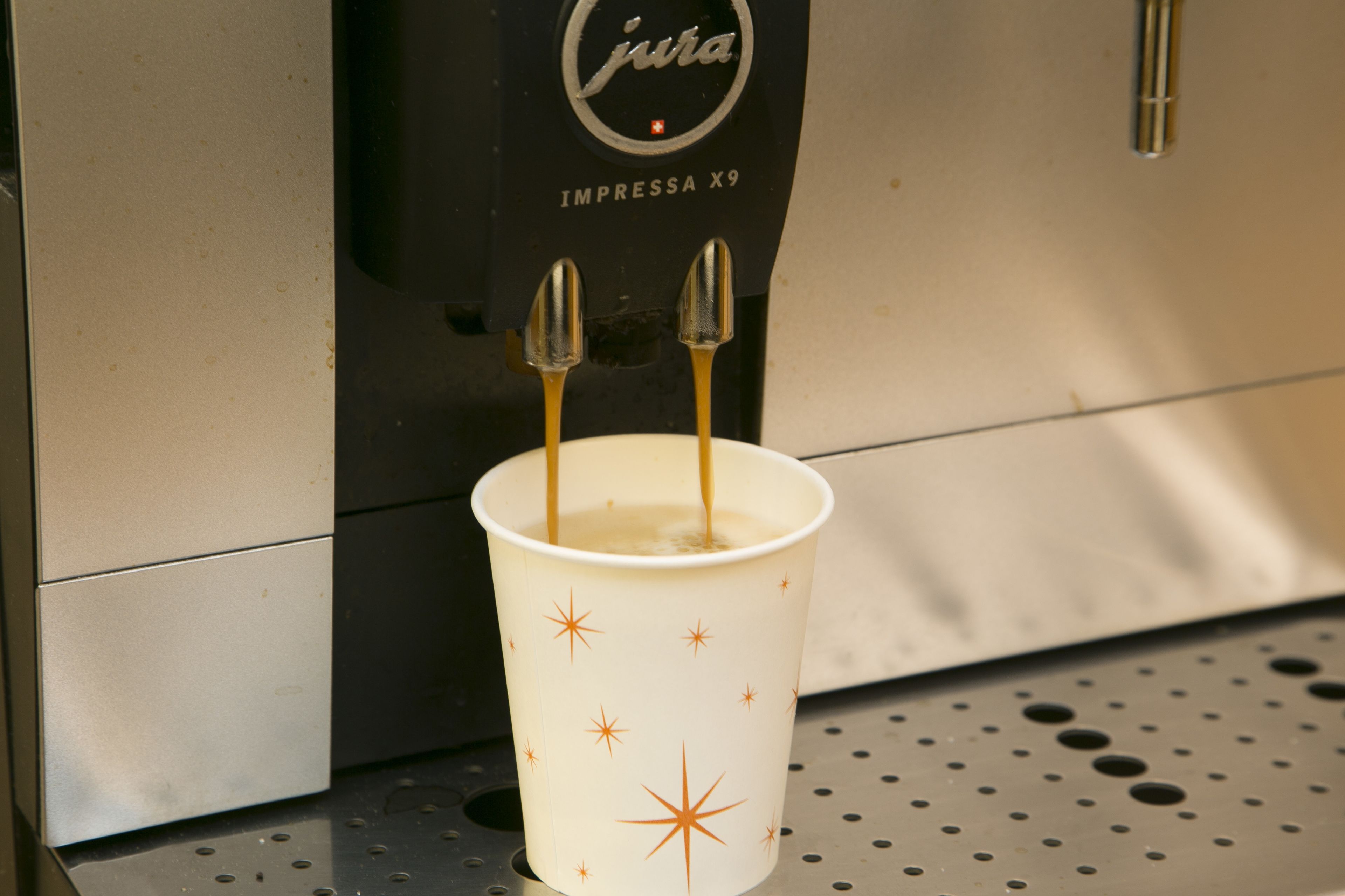 A coffee machine dispensing espresso into a cup with a star pattern.