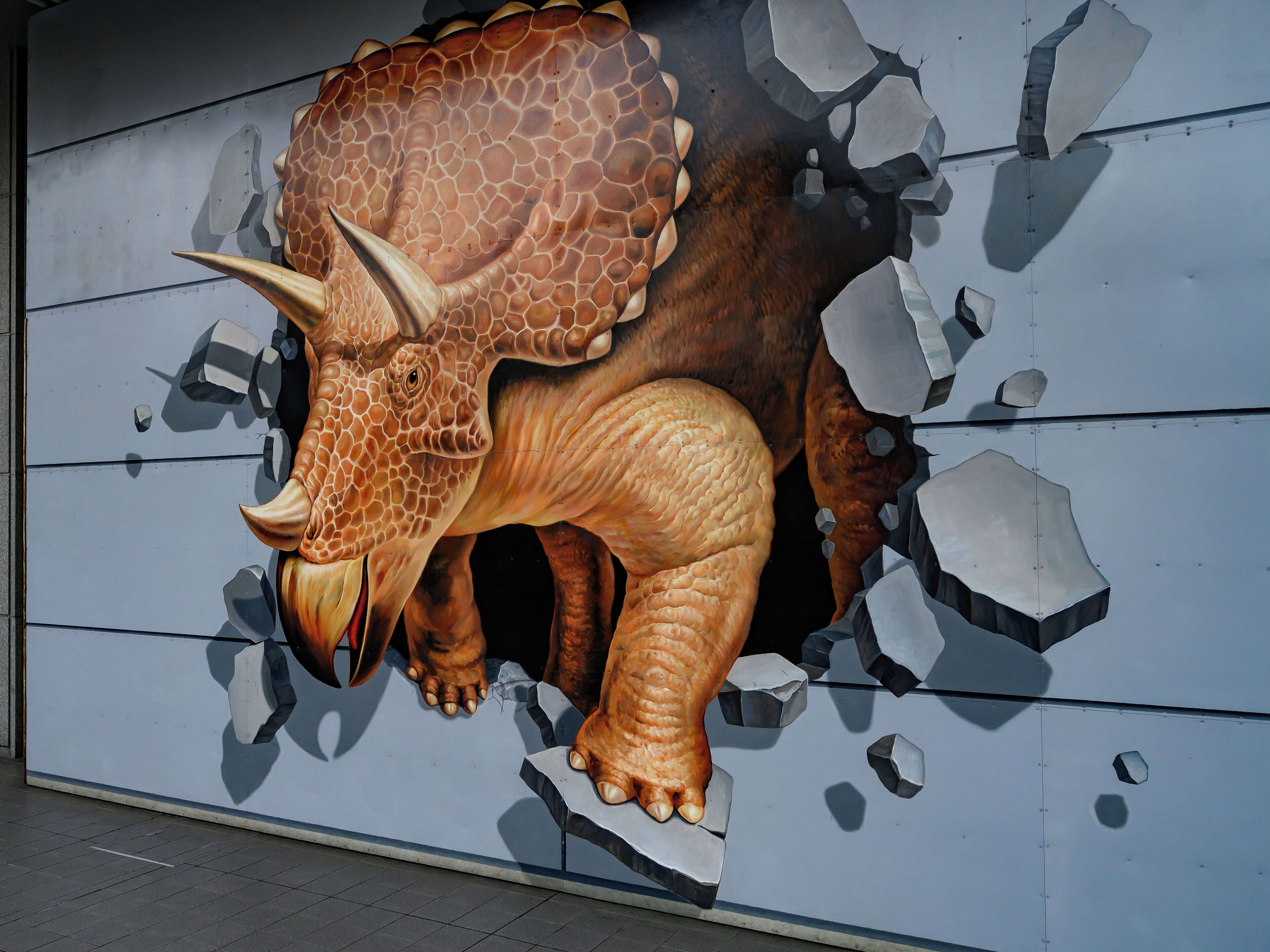 Un mural que muestra un triceratops rompiendo una pared.