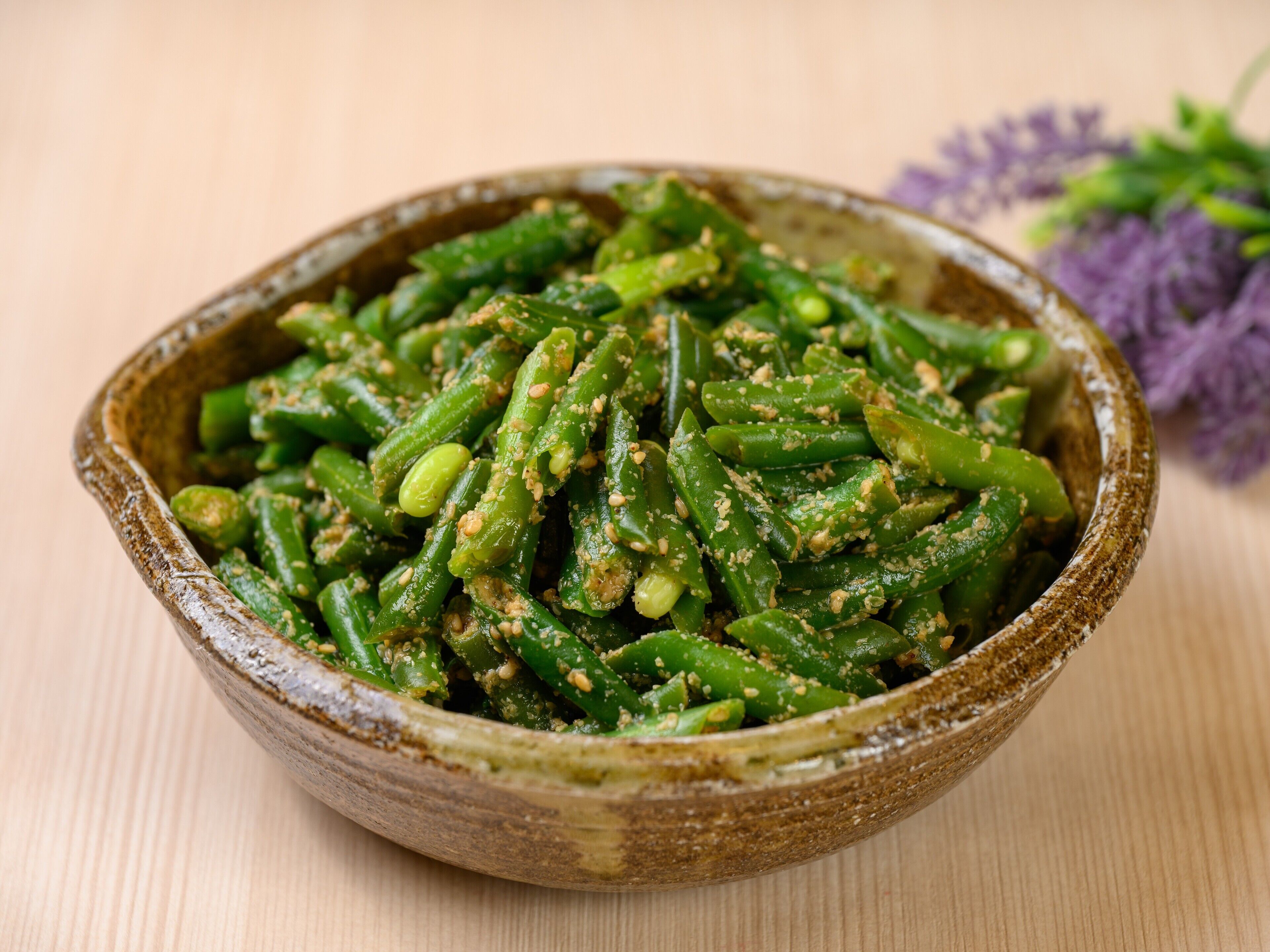 Un tazón de verduras verdes con nueces, sobre una superficie de madera.