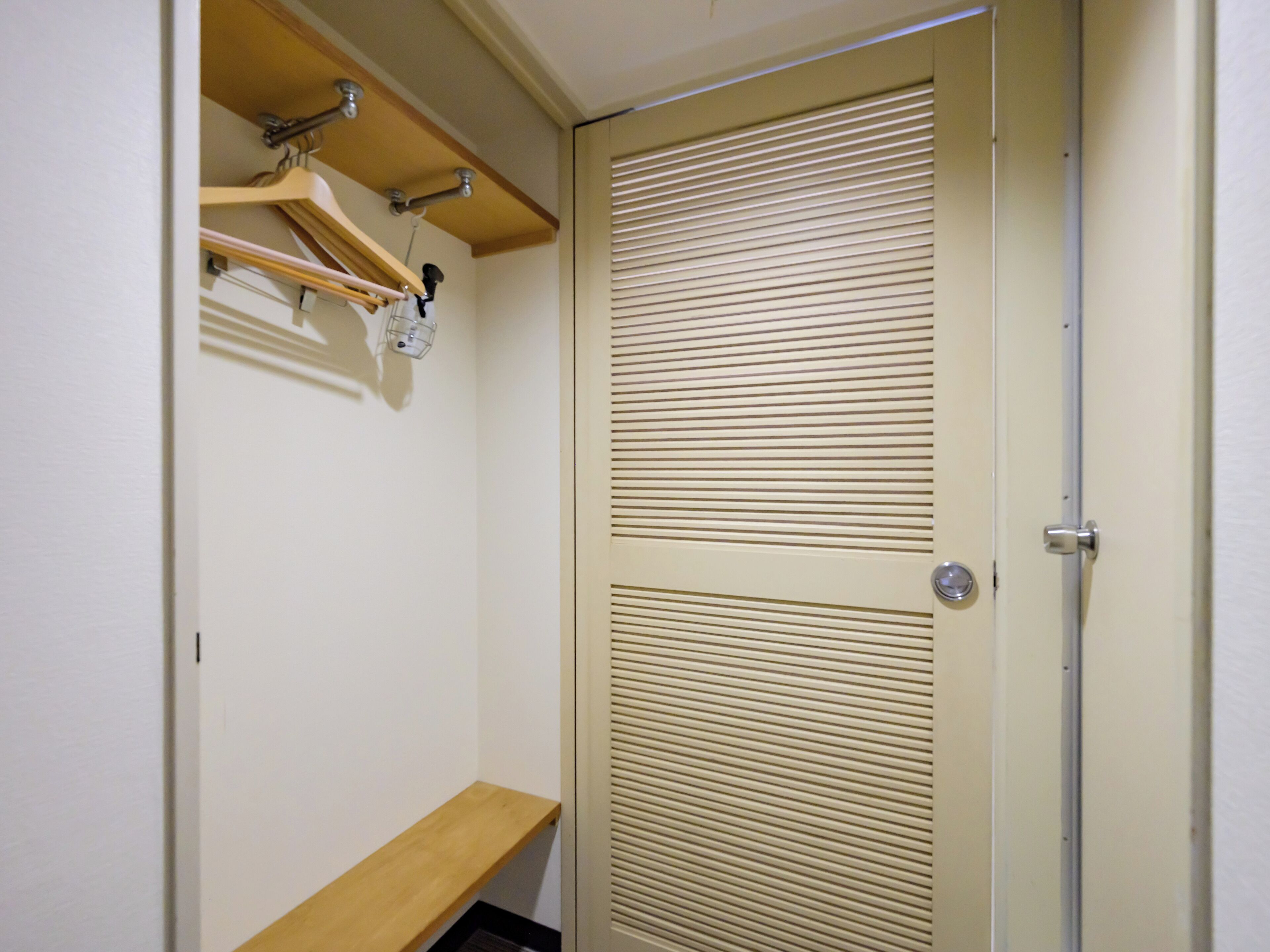 Een kast met een houten plank en een deur met horizontale spijlen.