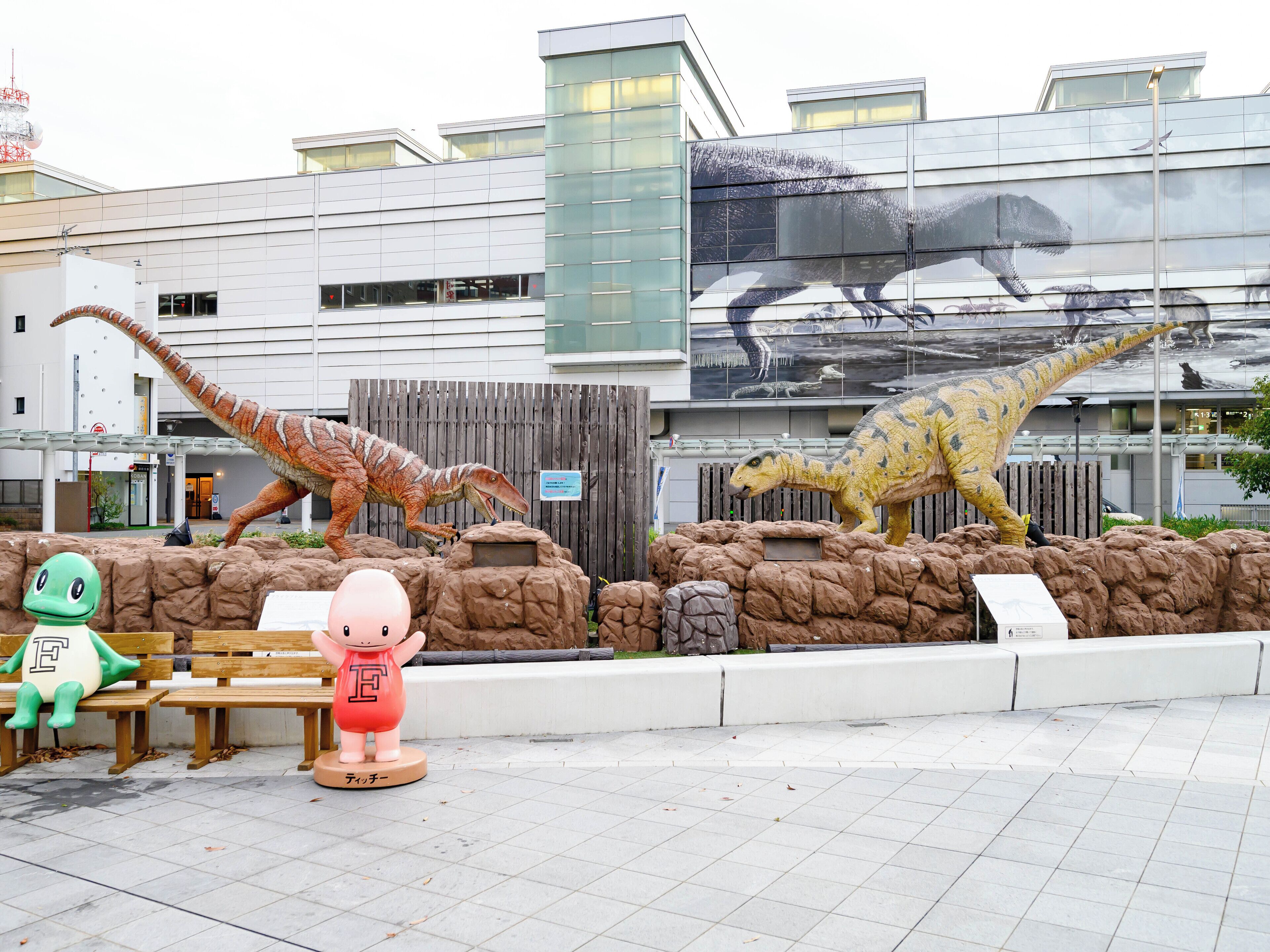 A dinosaur-themed exhibit with life-sized models and a mascot statue.