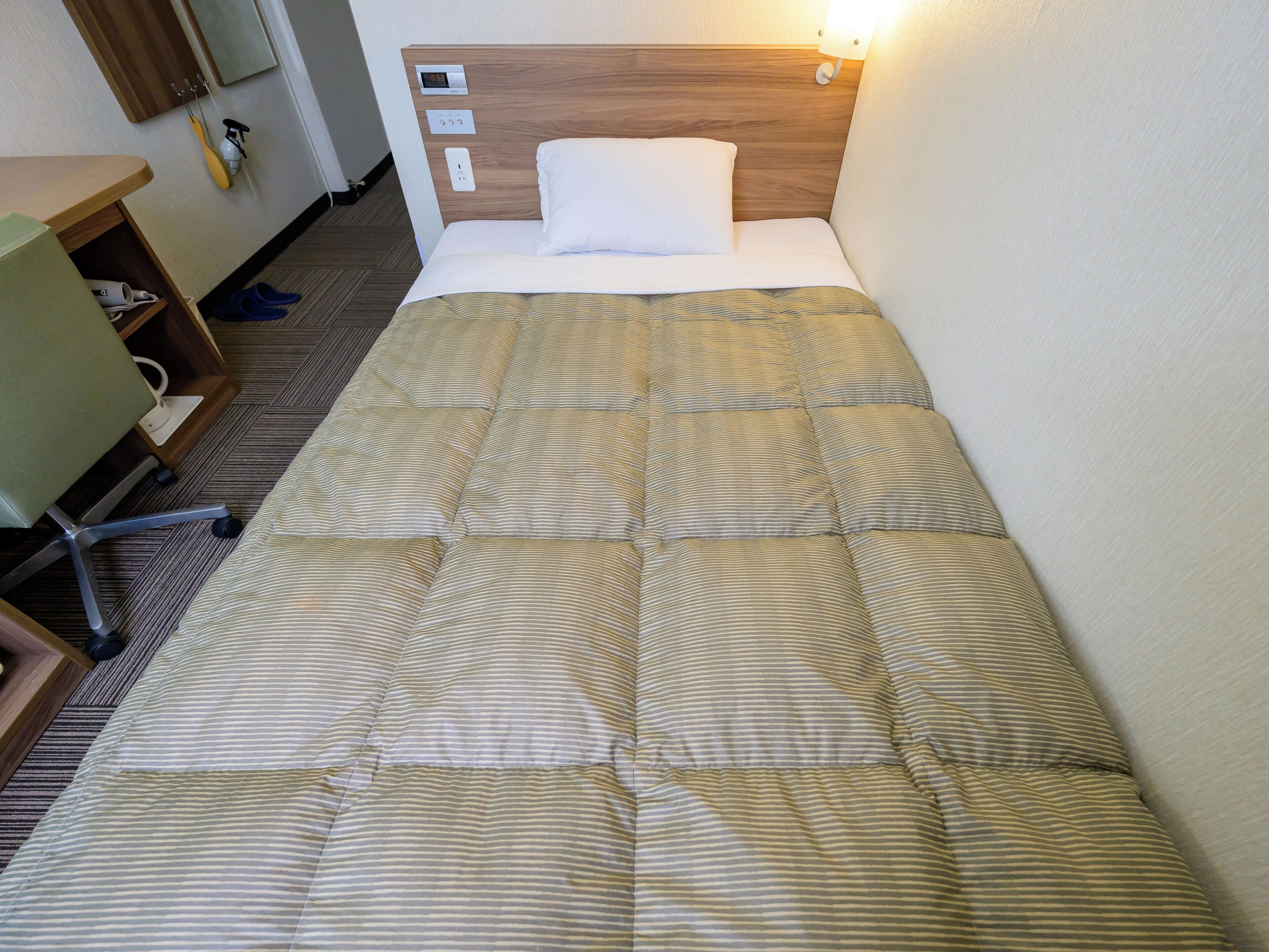 A hotel room with a bed, a desk, and a chair.
