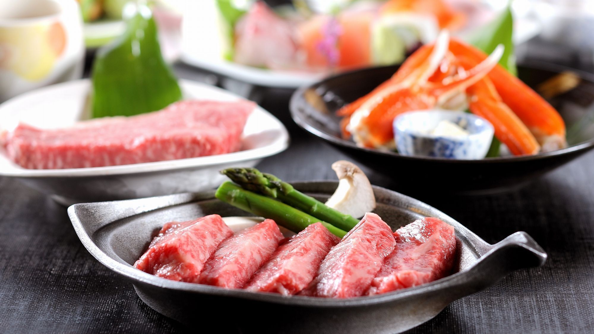 A variety of dishes including raw meat, vegetables, and seafood, suggesting a dining setting.