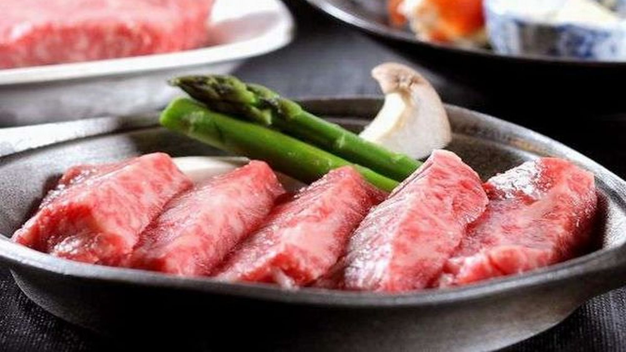 A plate with sliced meat, asparagus, and mushrooms.