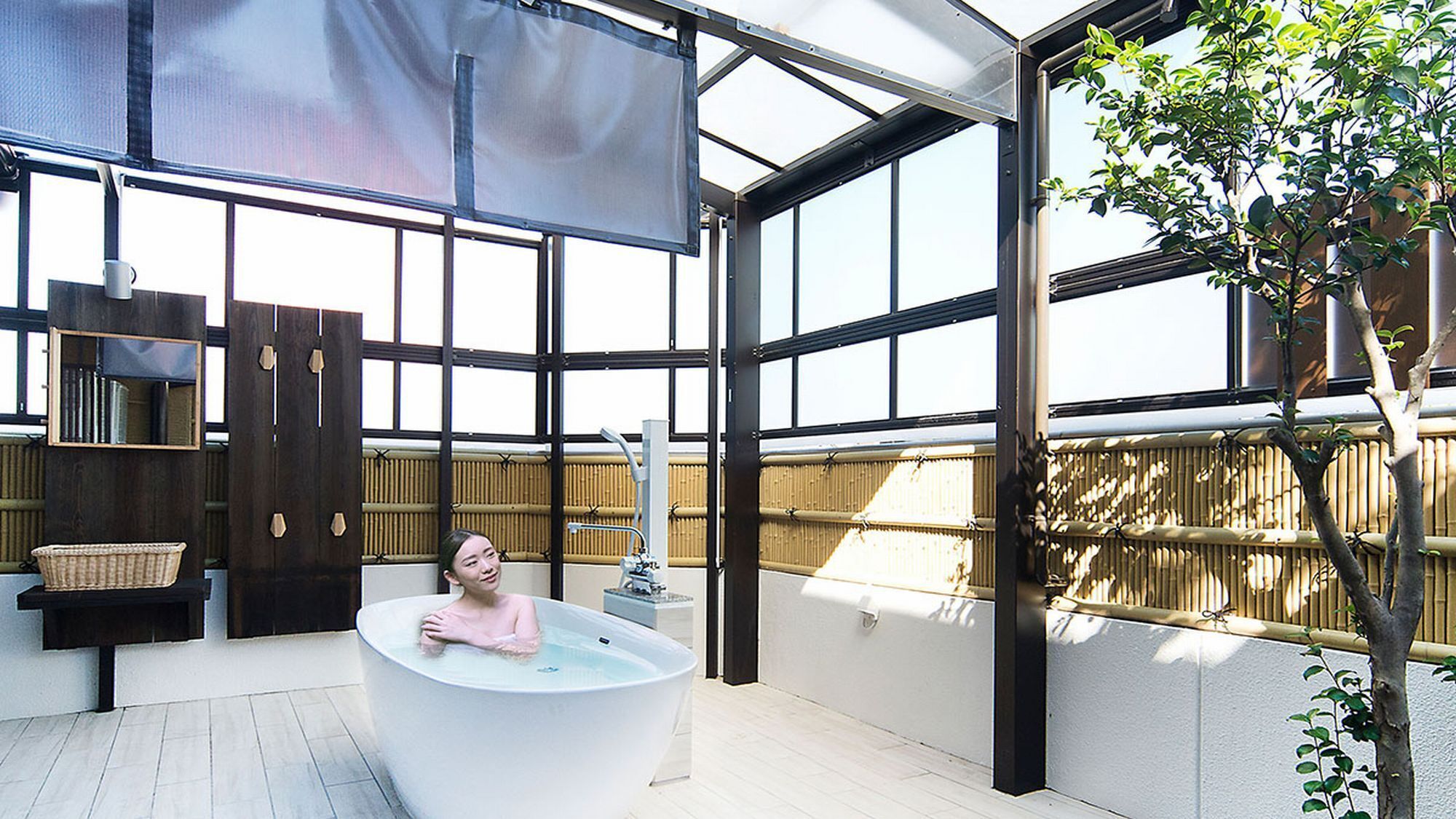A modern bathroom with a large bathtub, a wooden bench, and a bamboo wall.
