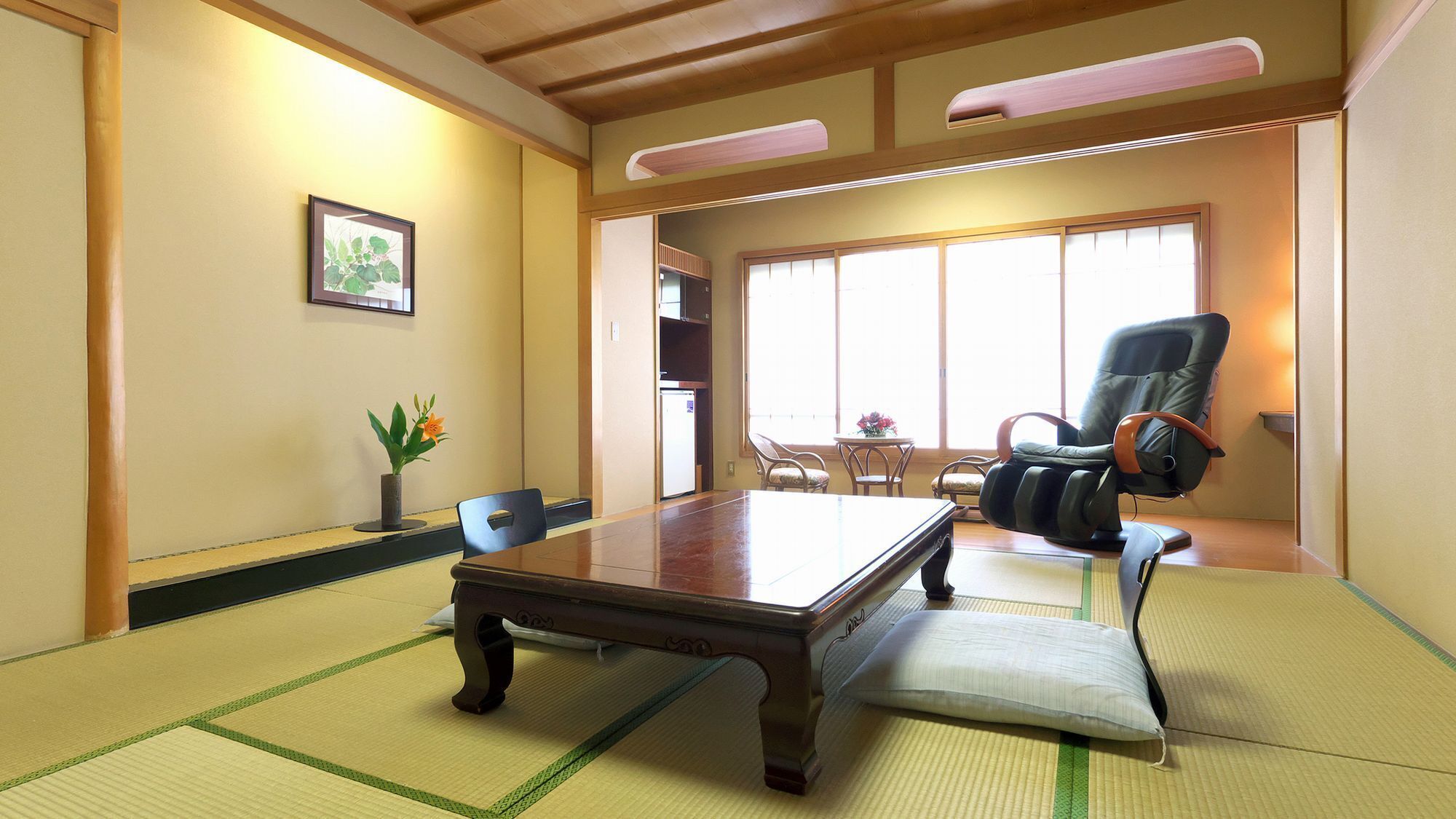 A traditional Japanese-style room with tatami flooring, a low table, a black leather chair, and a large window.