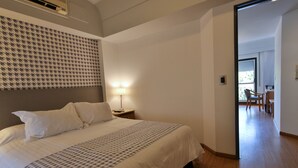 Habitación de hotel con una cama grande, un cabecero estampado, una lámpara de noche y vistas al comedor.