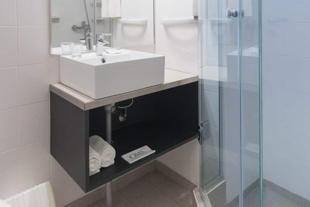 Un baño moderno con cabina de ducha de vidrio, un lavamanos blanco y un espejo grande.