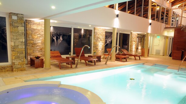 A pool area with lounge chairs, a hot tub, and stone walls. - La Campiña Club Hotel & Spa (Santa Rosa de Toay)