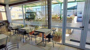 Ein Restaurant mit Außenbereich, Tischen, Stühlen und Blick auf die Straße und die Gebäude.
