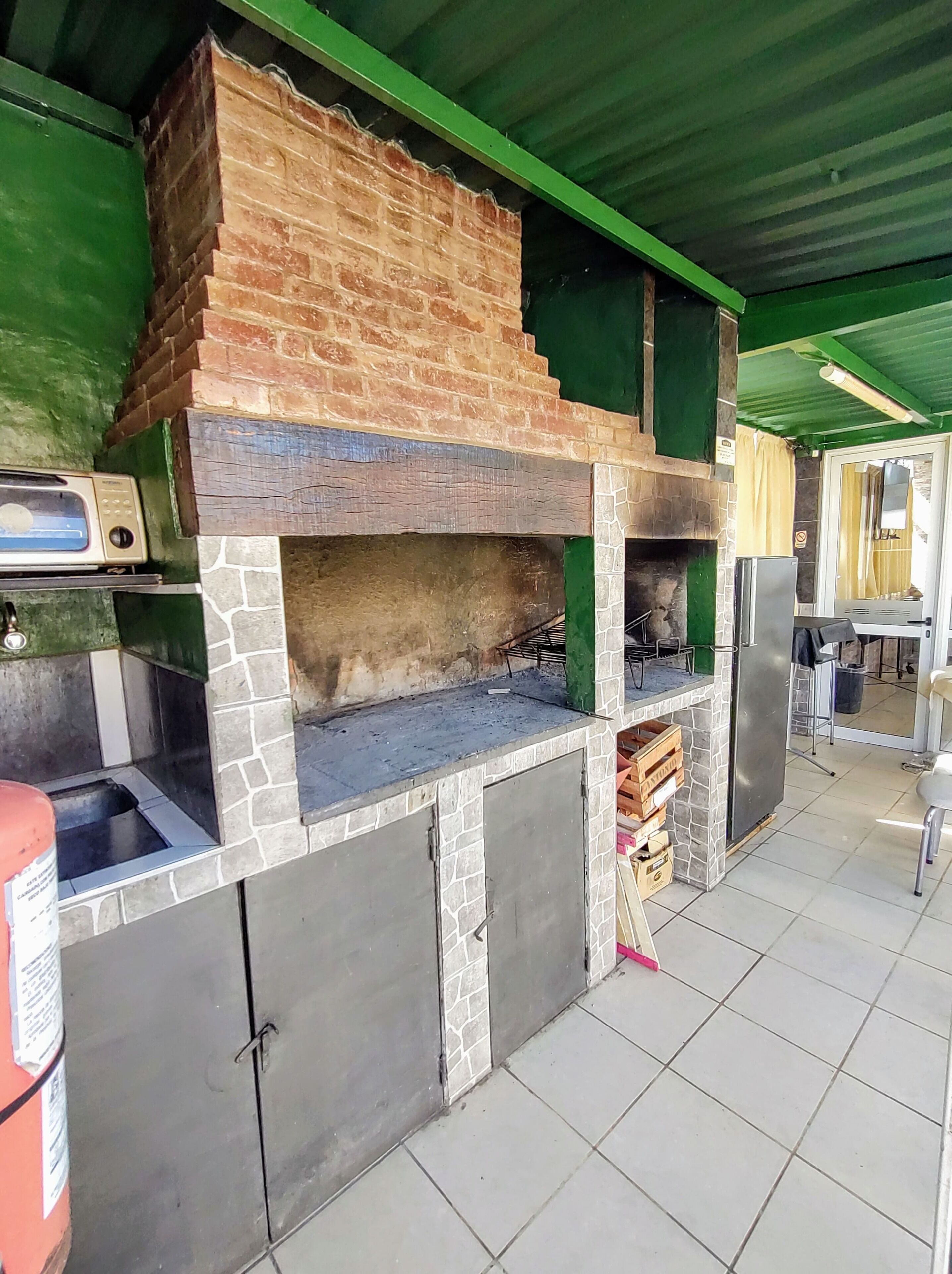 An outdoor kitchen area with a brick oven, a built-in grill, and a refrigerator.