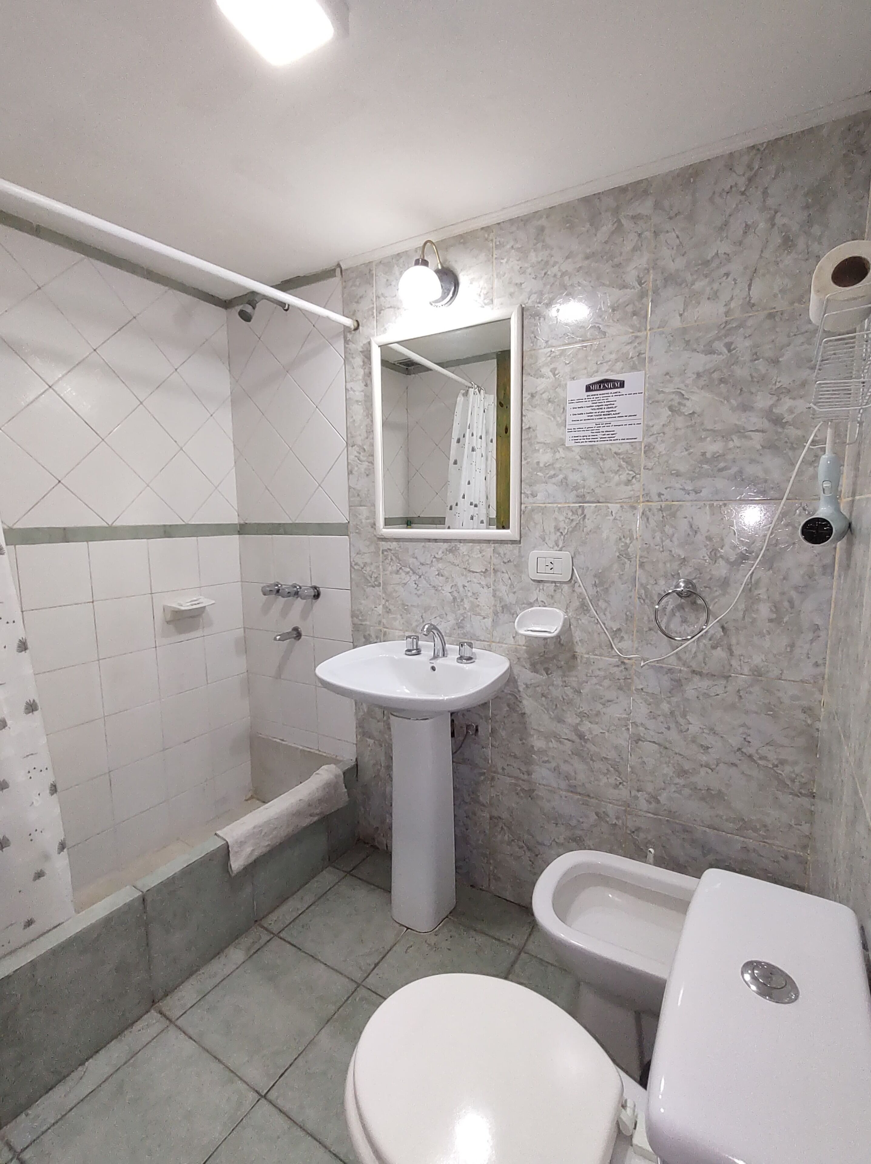 A bathroom with a shower, sink, toilet, and a mirror.
