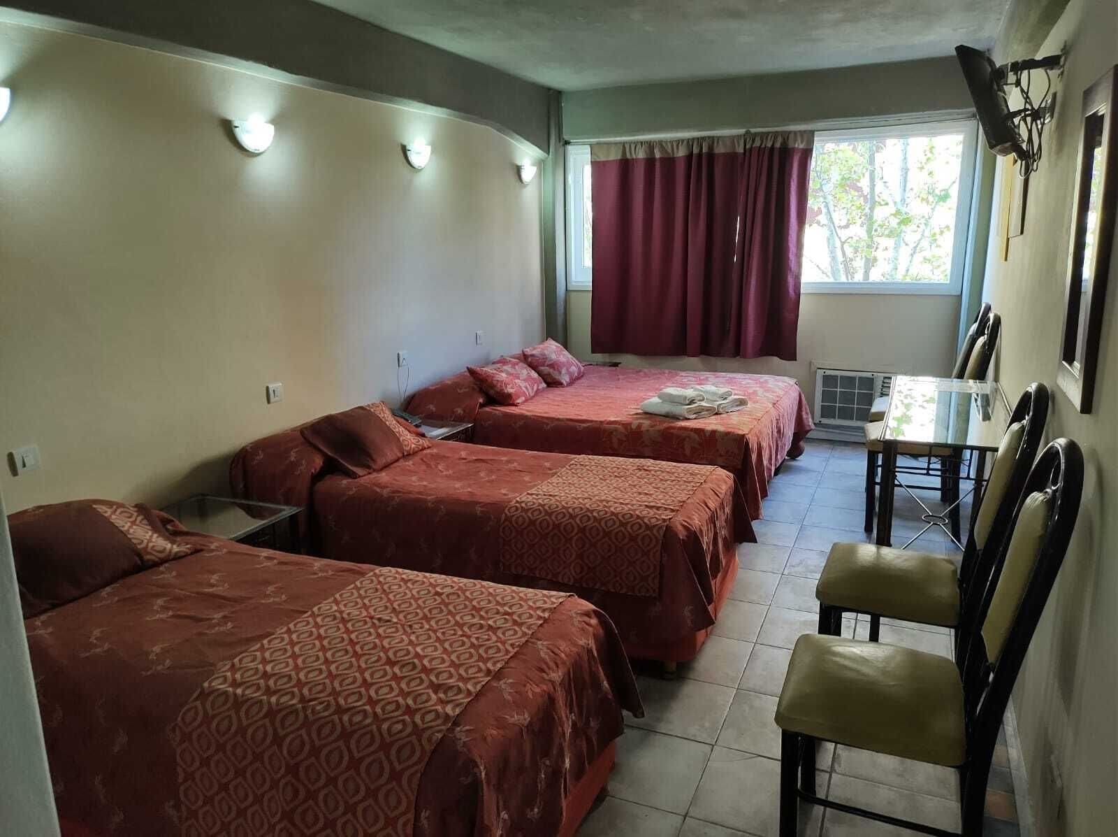 A hotel room with two beds, a dining table, and chairs.