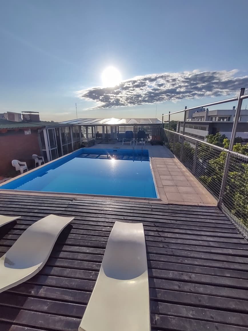 Piscina en la azotea con vistas despejadas al cielo y edificios cercanos.