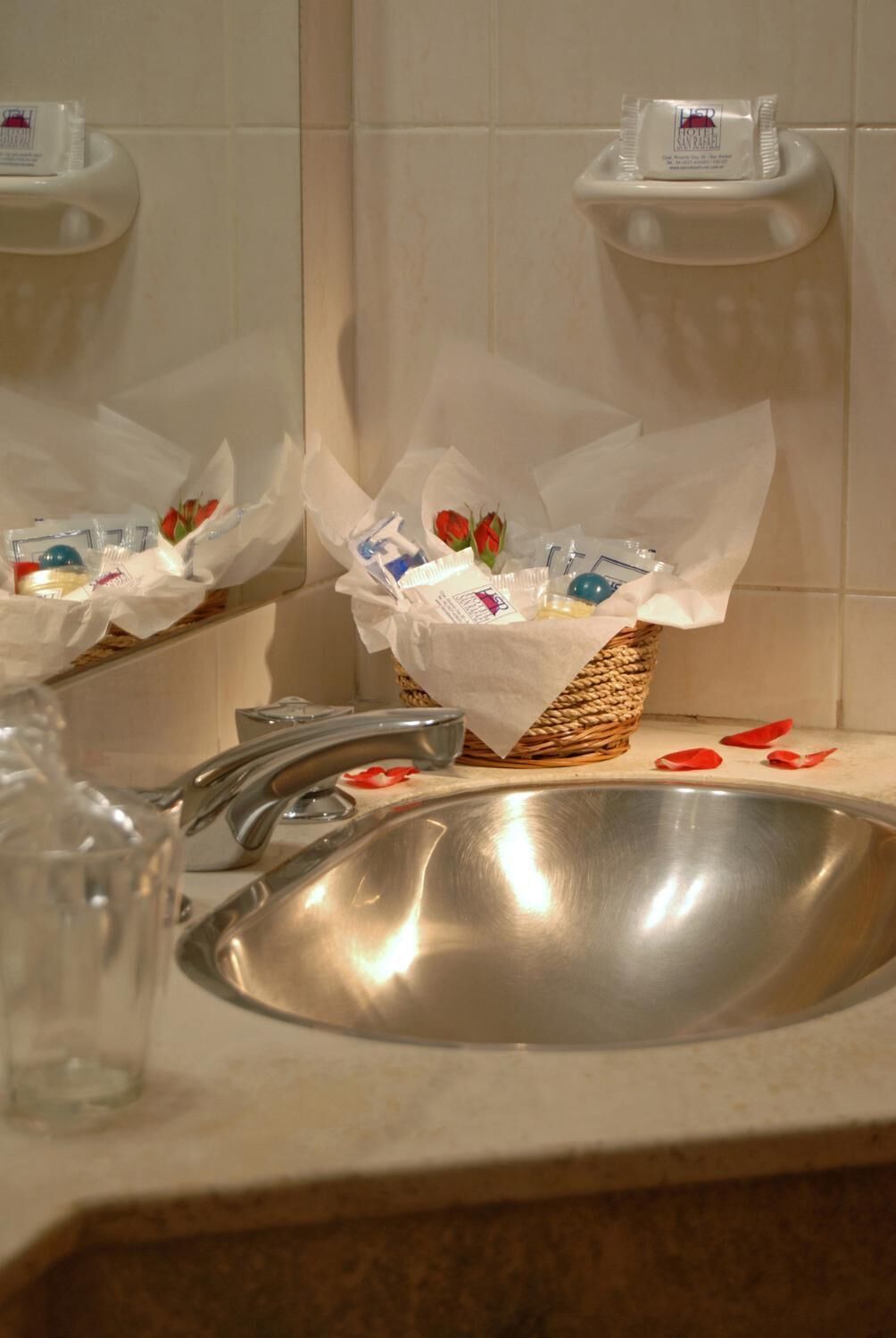 Un bagno con un lavandino, uno specchio e un cesto di articoli da toilette.