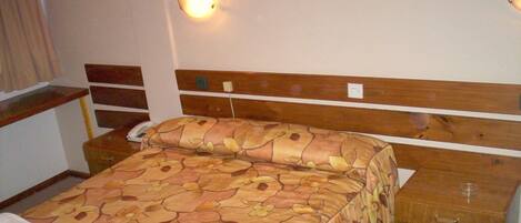 Habitación de hotel con cama, mesita de noche y una lámpara de pared.