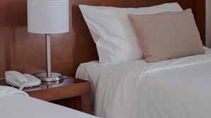 A hotel room with a bed, white bedding, a bedside lamp, and a telephone on a wooden nightstand. - Herradura Hotel Suites (Neuquen)