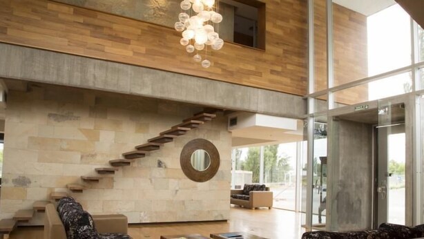 A spacious living area with a modern staircase, a large mirror, and a contemporary chandelier. - Herradura Hotel Suites (Neuquen)