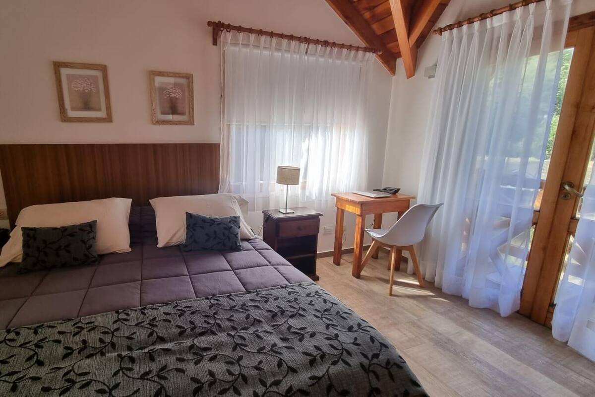 Un dormitorio con una cama grande, dos mesitas de noche, un escritorio y una silla.